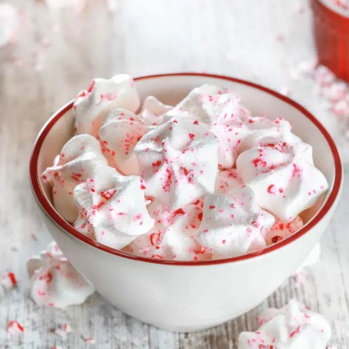 Small white bowl full of Mini Peppermint Meringue Cookies. Recipe from A Kitchen Addiction